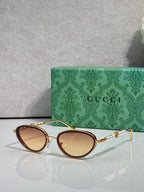 Gold oval sunglasses with warm brown gradient lenses and ornate chain-link arms