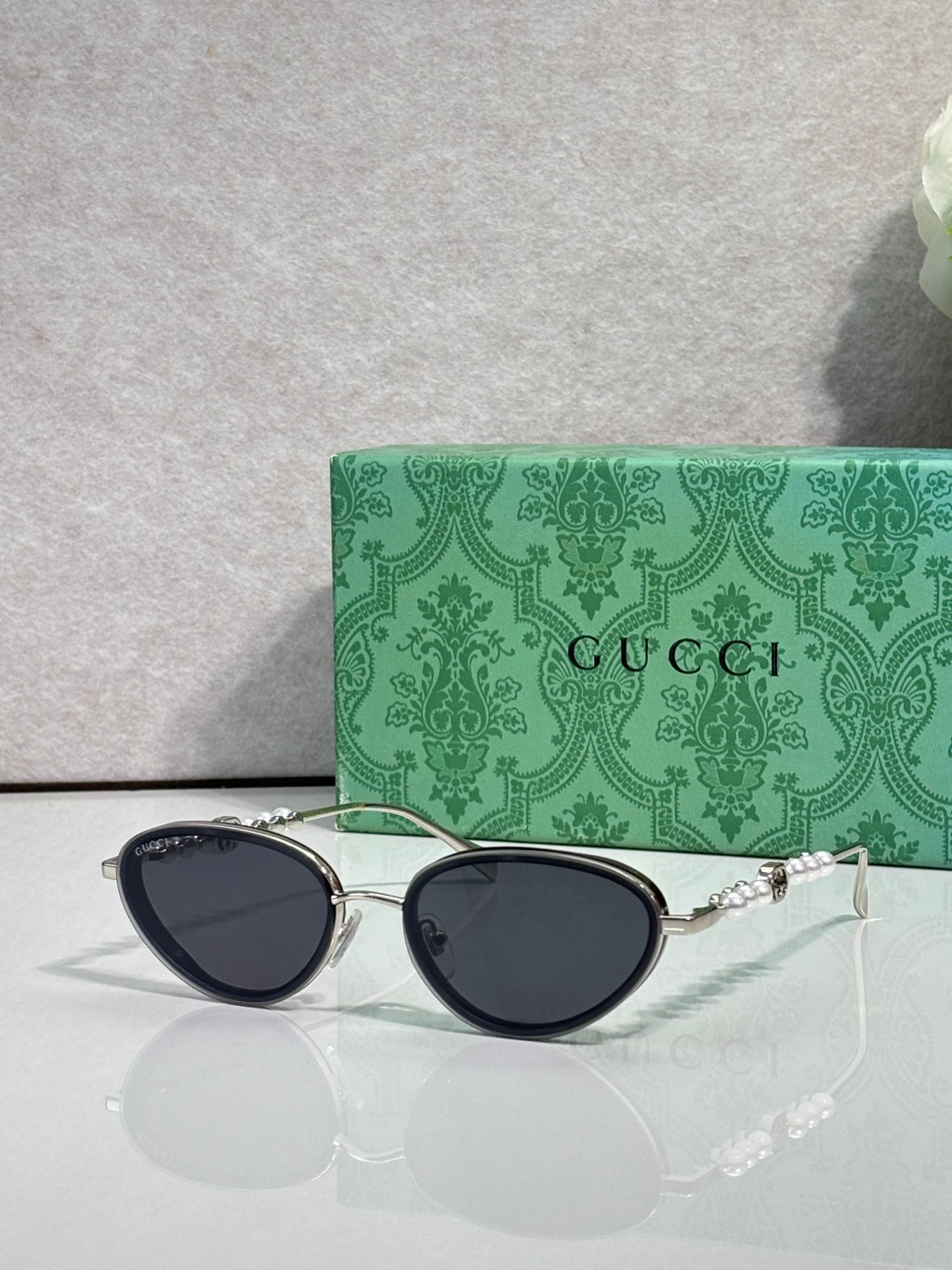 Silver oval sunglasses with dark navy lenses and chain-link decorative arms