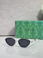 Silver oval sunglasses with dark navy lenses and chain-link decorative arms