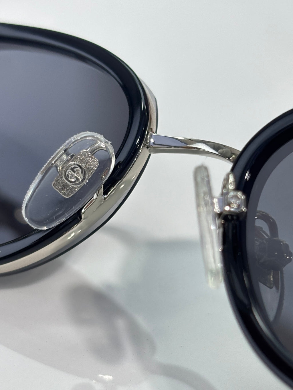 Close-up of glossy black sunglasses lens with metal logo plate on frame