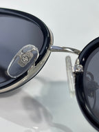 Close-up of glossy black sunglasses lens with metal logo plate on frame