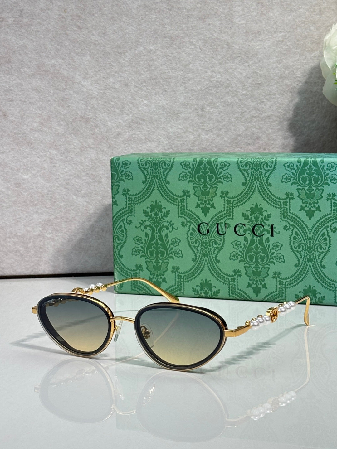 Gold oval sunglasses with gradient green lenses and decorative chain-link arms