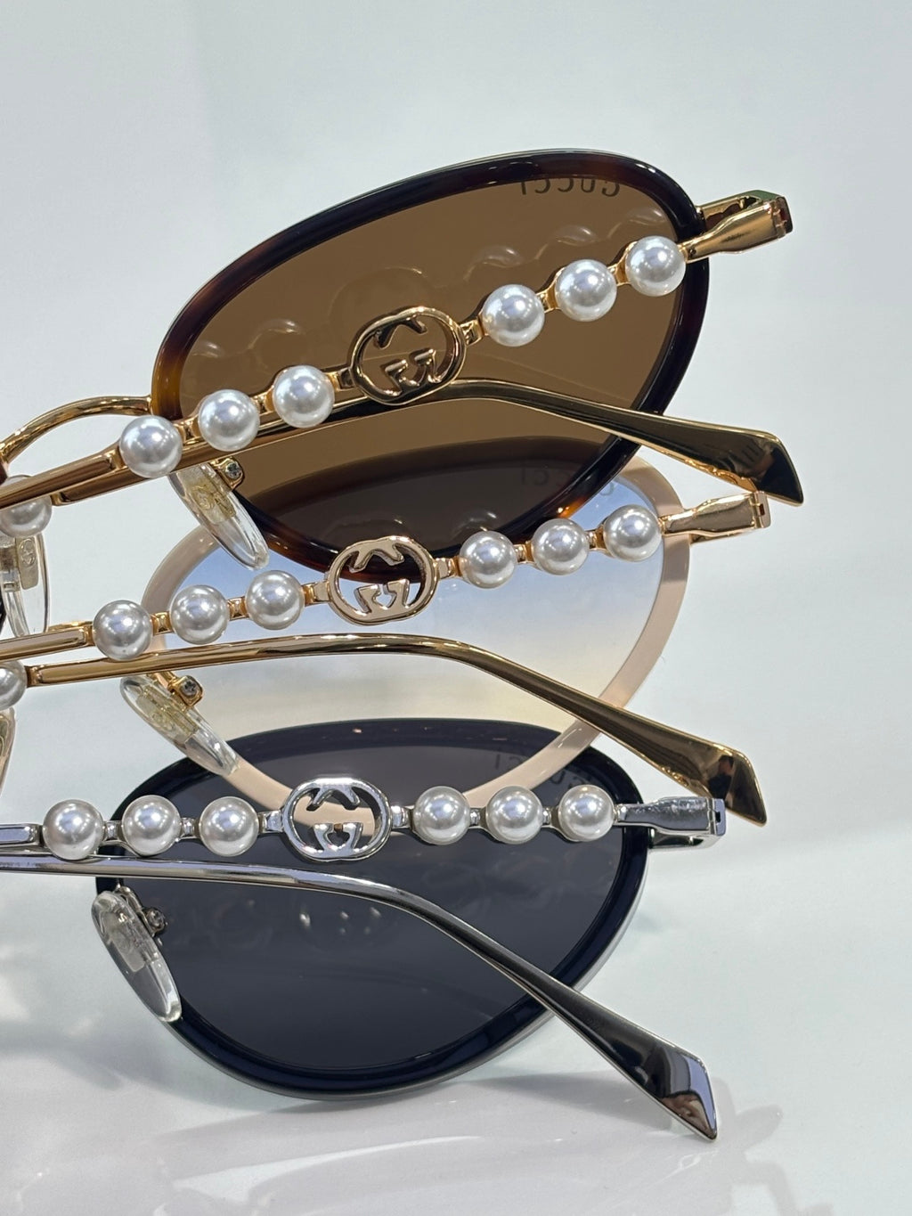 Gold sunglasses with dark lenses featuring pearl-like beads and GG logo charms