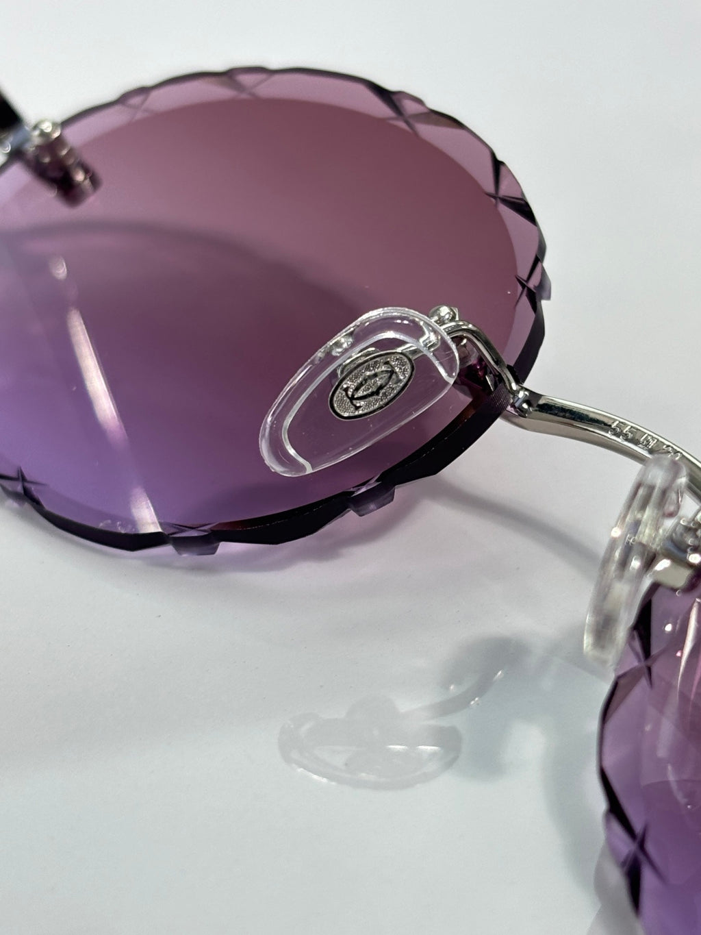 Cartier round eyeglass lens close-up with purple tint and metal rim
