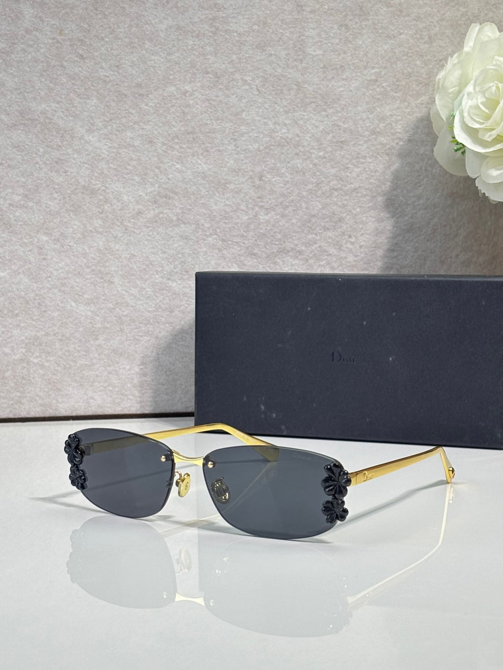 Dior sunglasses with dark lenses and gold frame, black floral details on temples
