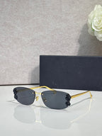 Dior sunglasses with dark lenses and gold frame, black floral details on temples