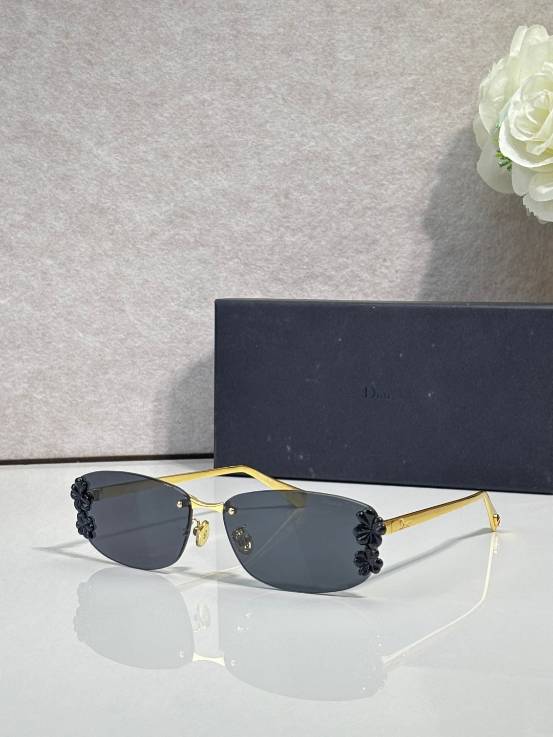 Dior sunglasses with dark lenses and gold frame, black floral details on temples