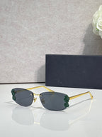 Dior sunglasses with dark lenses and gold frame, green floral details on temples