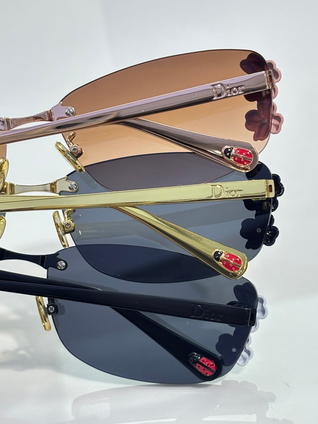 Dior sunglasses close-up, stacked frames in gold with floral temple details and lenses