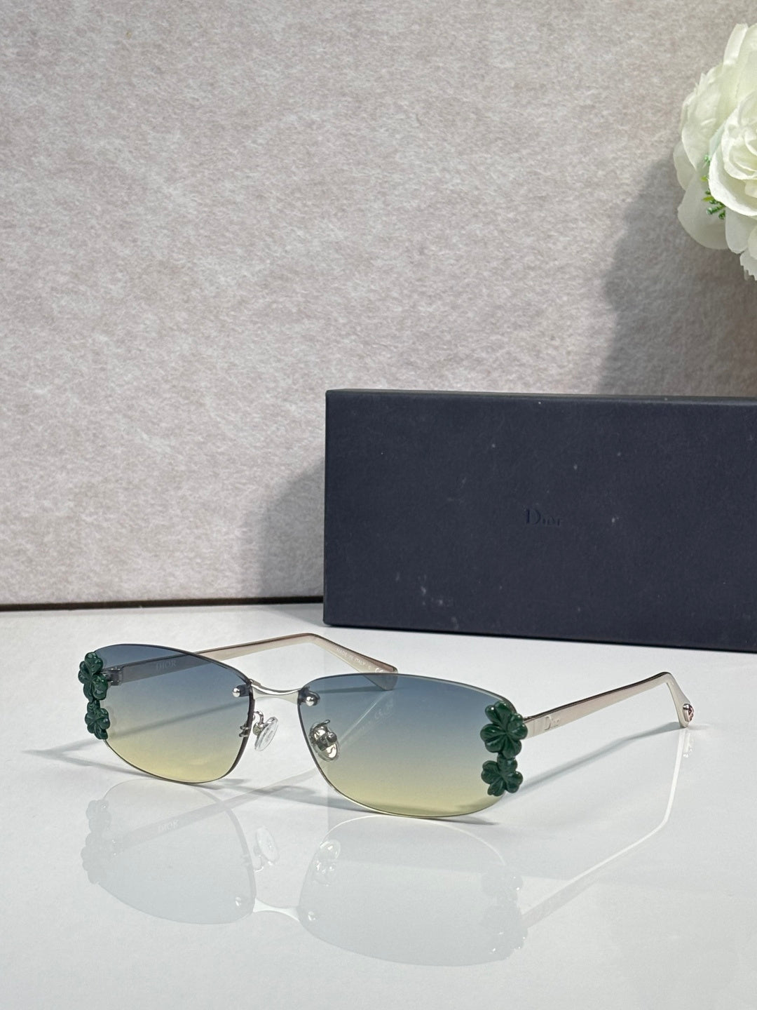 Dior sunglasses with green-tinted lenses and gold frame, green floral accents on temples