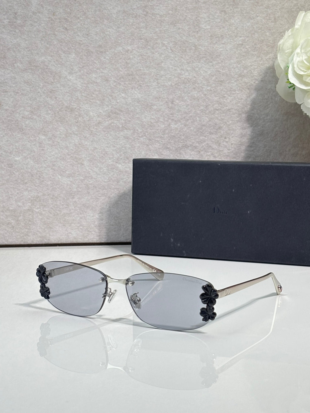 Dior sunglasses with clear lenses and dark floral accents on temples, thin metal frame