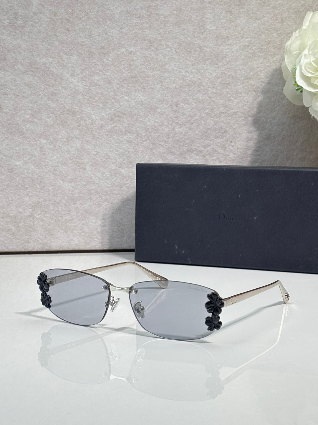 Dior sunglasses with clear lenses and dark floral accents on temples, thin metal frame