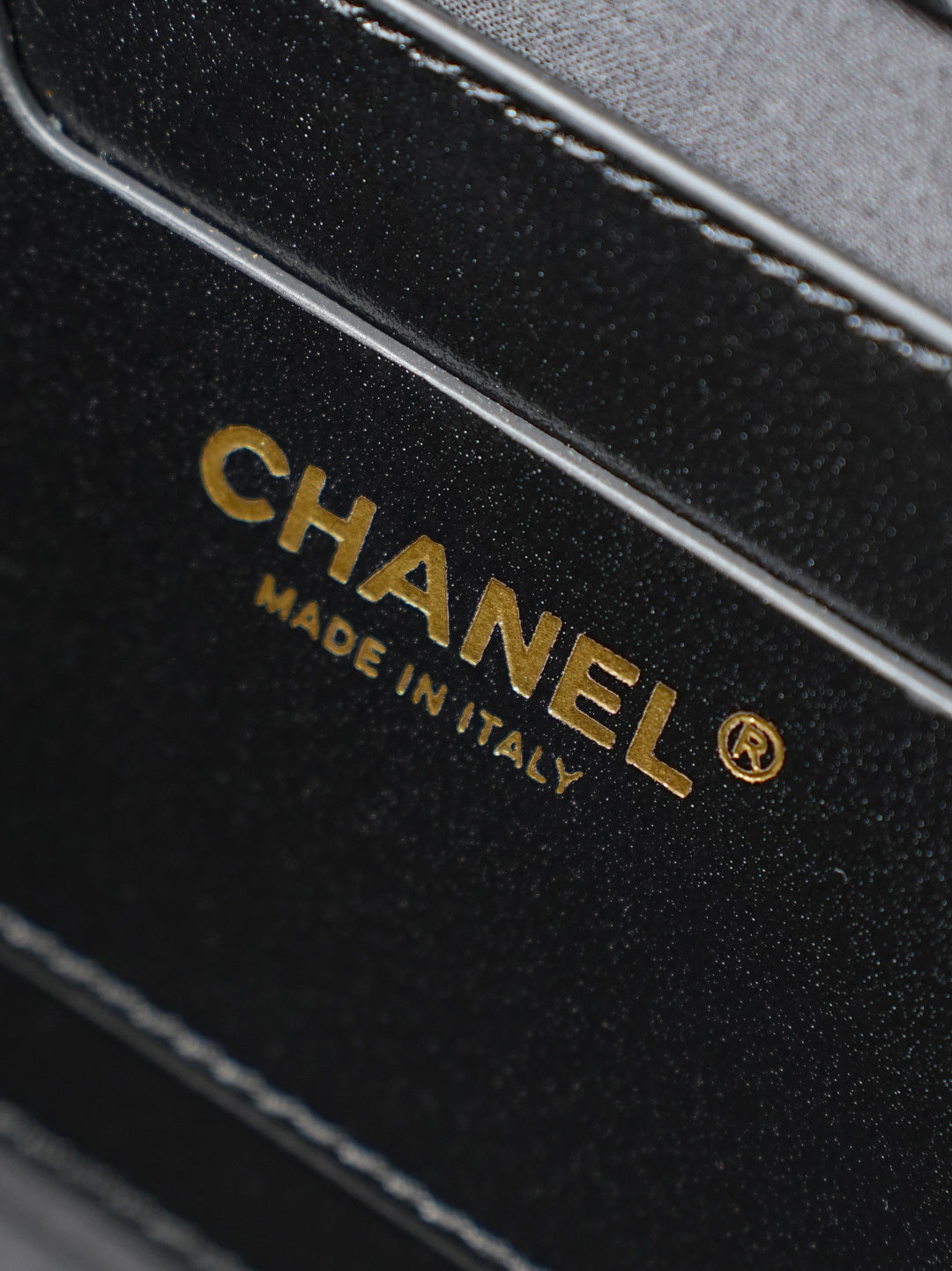 Chanel strap label reading “MADE IN ITALY” on black leather