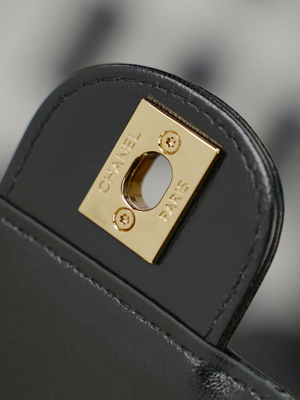 Chanel bag hardware close-up with gold square plate on black leather
