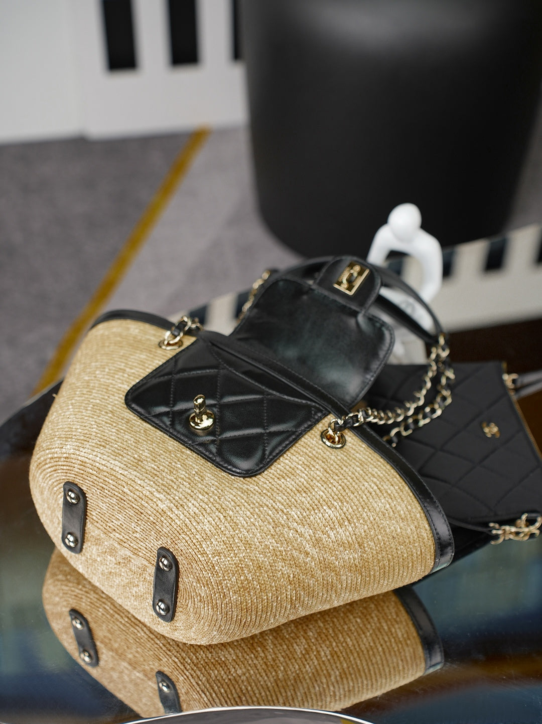 Chanel bag with woven straw body and black quilted flap detail, with gold chain and strap hardware