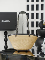 Chanel tote-style bag with woven straw base and black top handle, featuring chain straps