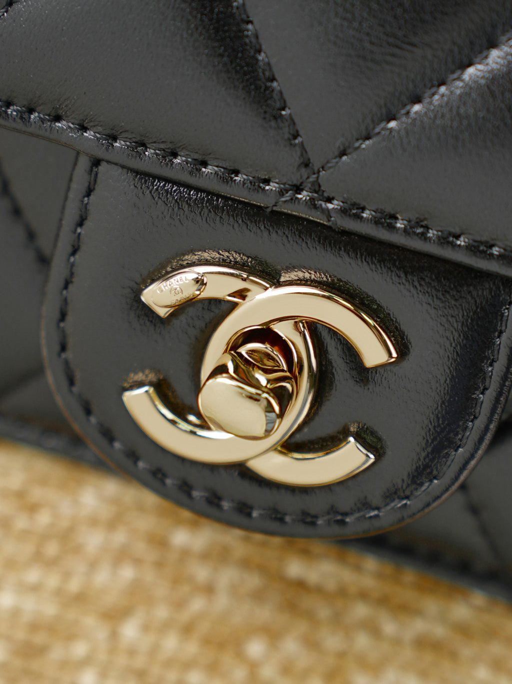 Chanel mini bag clasp close-up with gold CC emblem on black quilted leather