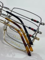 Gucci eyeglasses with curved temples featuring red, green, and blue stripe inlays
