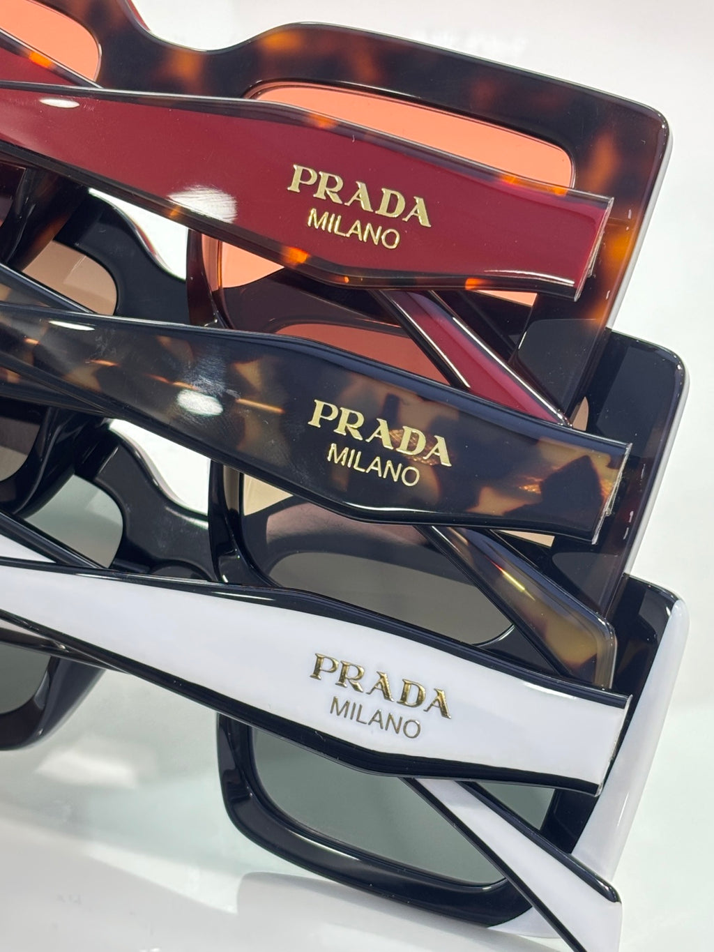 Prada sunglasses close-up: multiple frames with “PRADA MILANO” on temple inserts