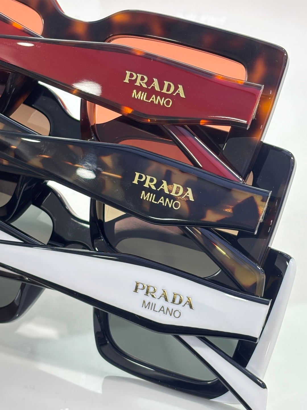 Prada sunglasses close-up: multiple frames with “PRADA MILANO” on temple inserts