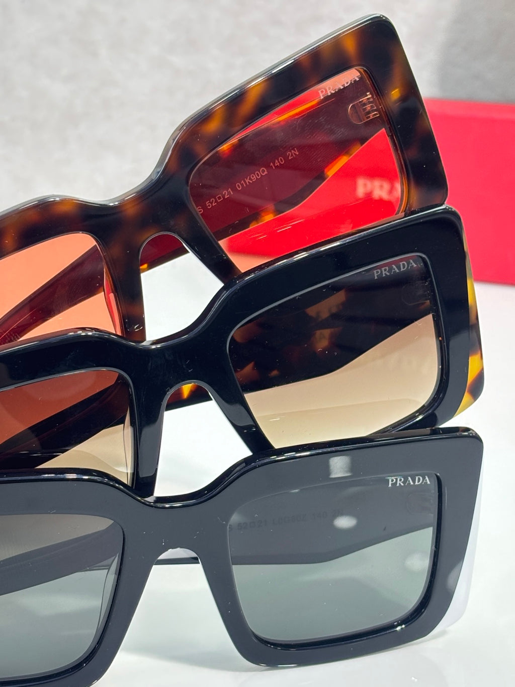 Prada sunglasses stacked view with tortoiseshell and dark frames; colored lenses visible