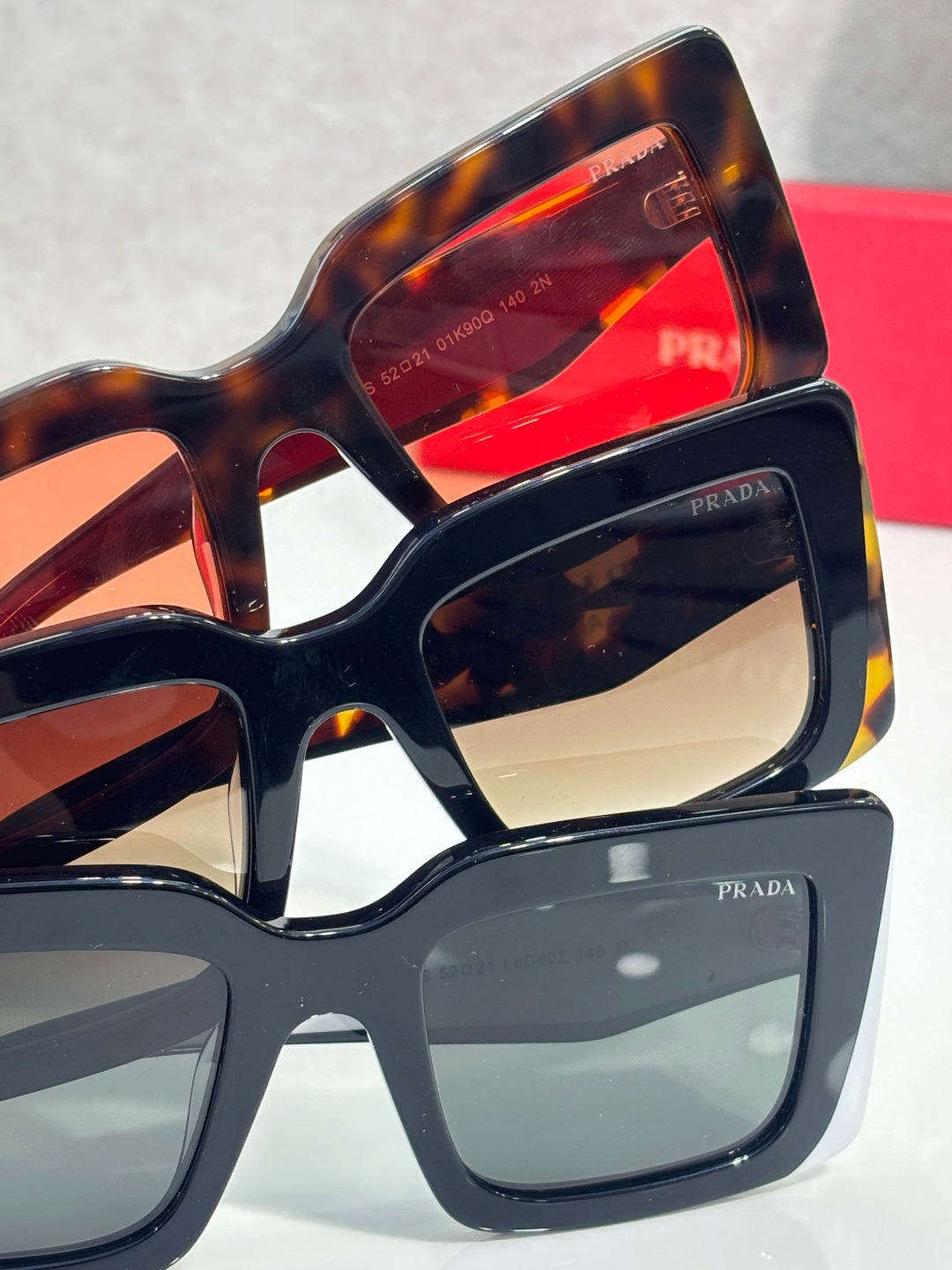 Prada sunglasses stacked view with tortoiseshell and dark frames; colored lenses visible