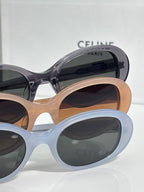 Celine sunglasses with light blue and tan frames, dark lenses, rounded cat-eye style