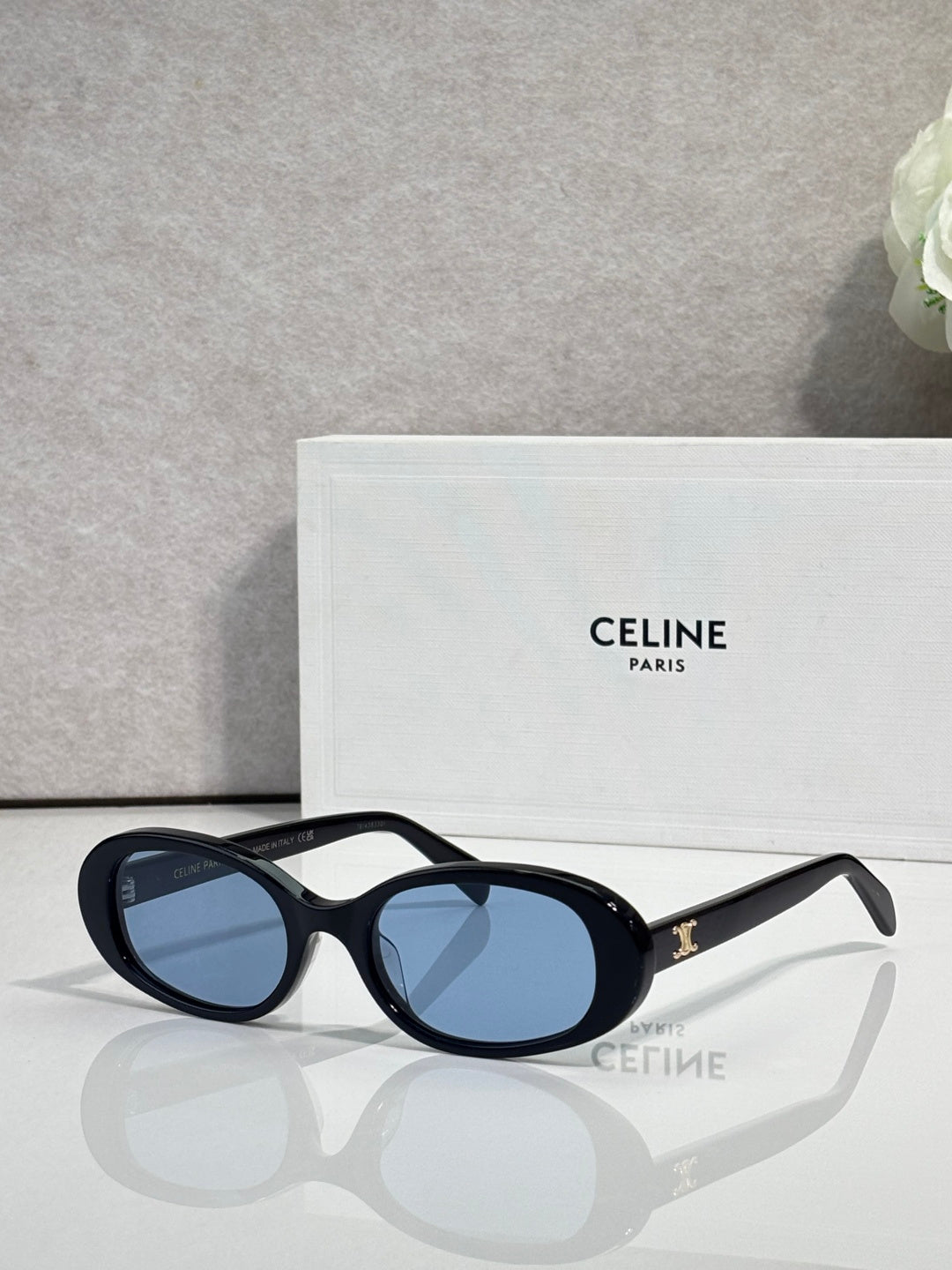 Celine sunglasses with black frame, blue oval lenses, and gold arm detail