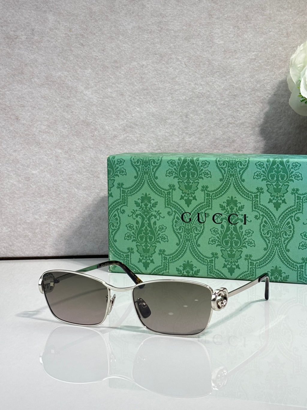 Gucci glasses with silver-tone frame and gray gradient lenses.