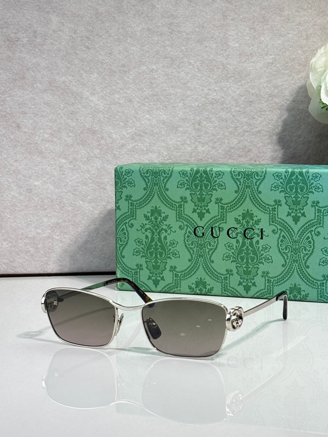 Gucci glasses with silver-tone frame and gray gradient lenses.