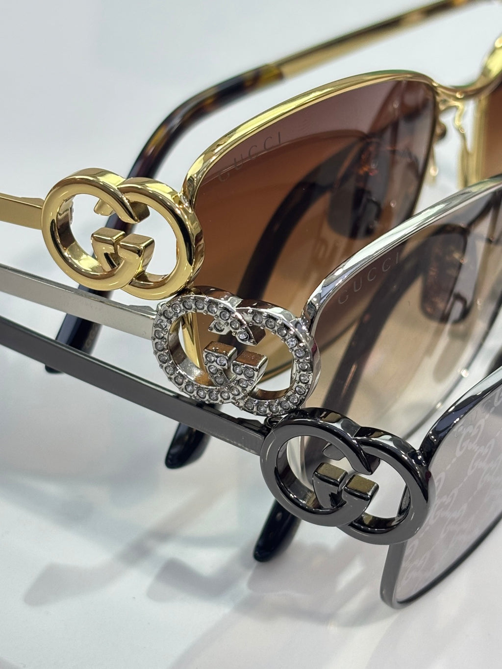 Gucci glasses close-up: gold-tone chain emblem with rhinestone details.