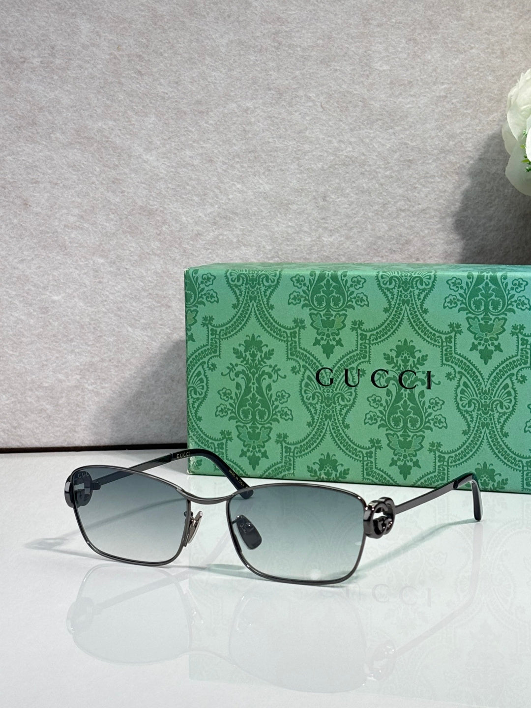 Gucci glasses with black frame and light gray-blue gradient lenses.
