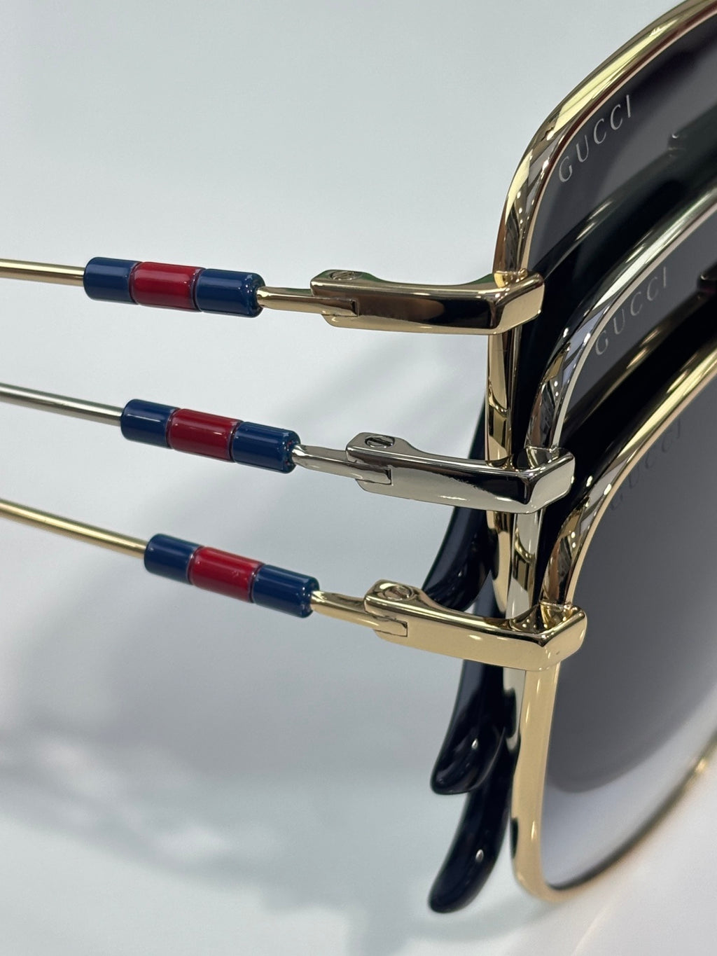Sunglasses temple detail with gold arms and red/blue stripe accents
