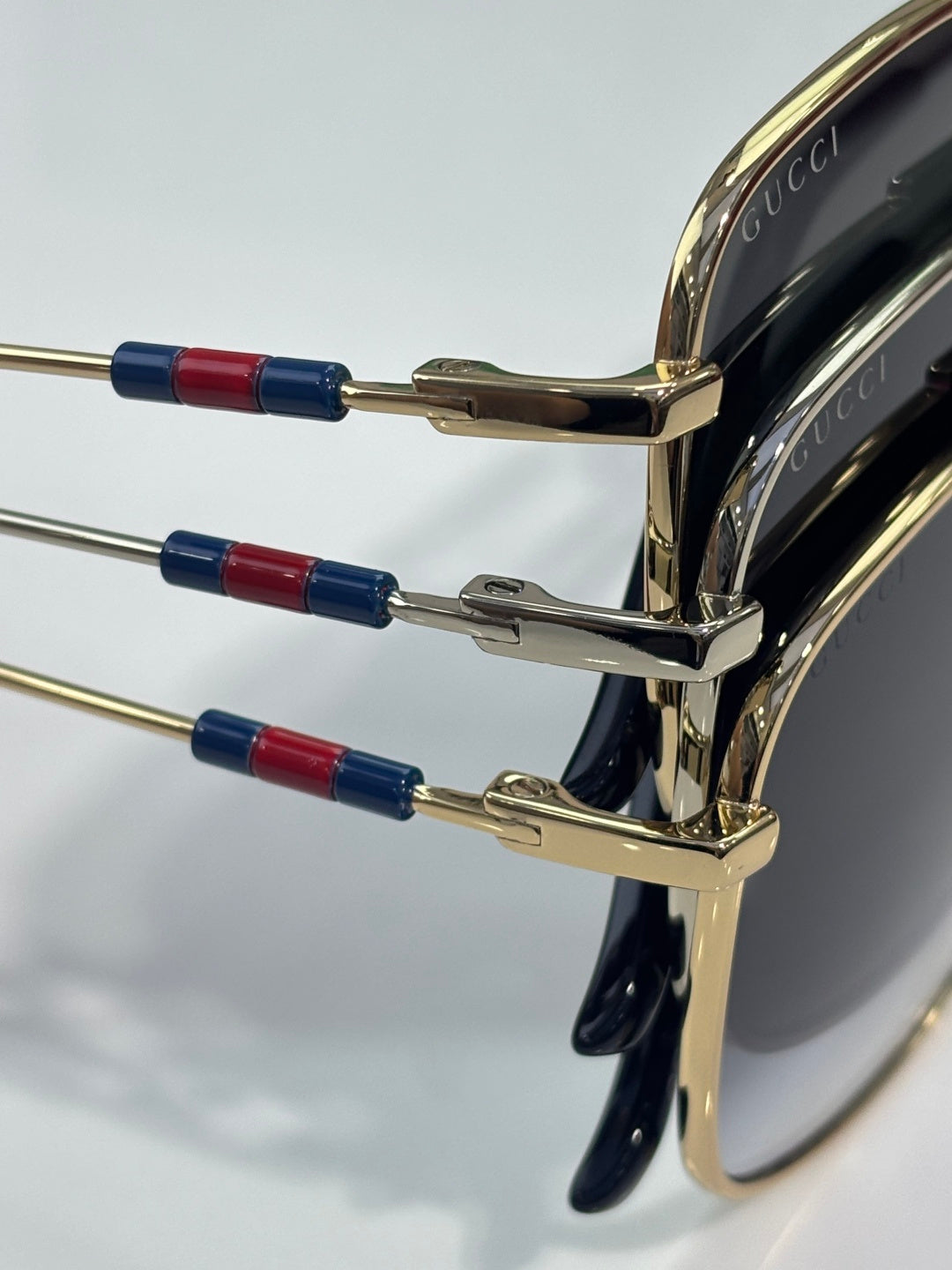 Sunglasses temple detail with gold arms and red/blue stripe accents