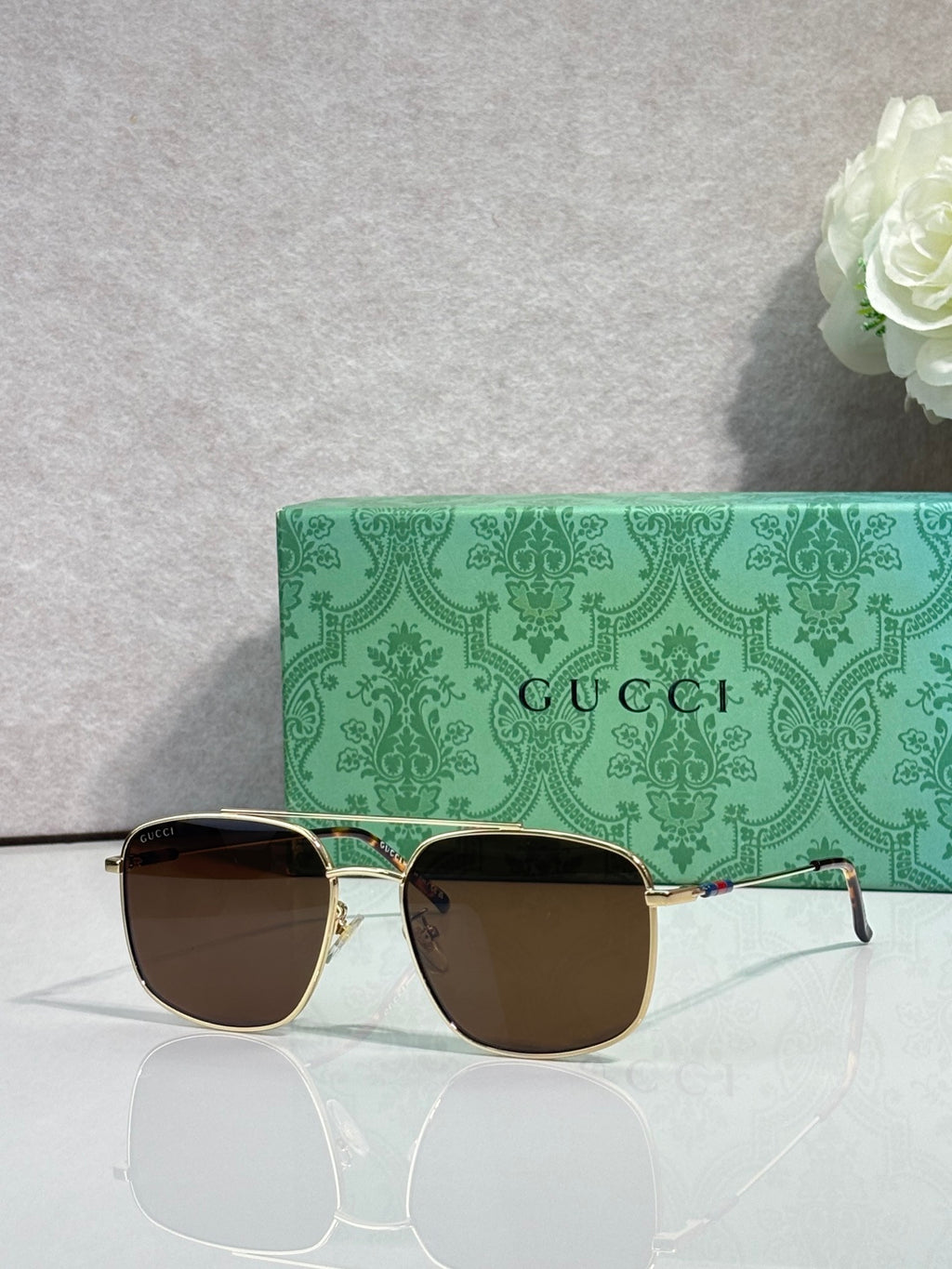 Sunglasses with gold frame, dark gradient lenses, and black top rim detail