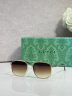 Sunglasses with gold frame and gradient dark lenses, black top rim