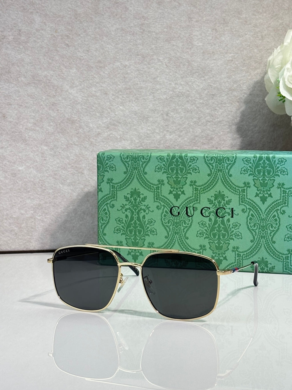 Sunglasses with gold frame and black-tinted lenses, square aviator shape
