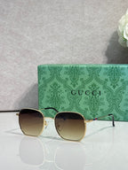 Gold-tone square sunglasses with dark lenses, shown with a green branded case