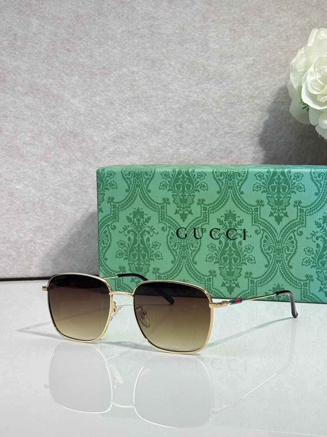 Gold-tone square sunglasses with gradient lenses and green temples, front view