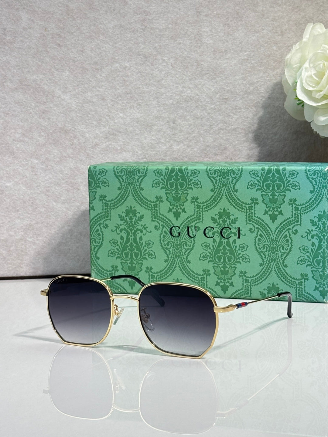 Gold-tone square sunglasses with dark lenses and green temples, side view