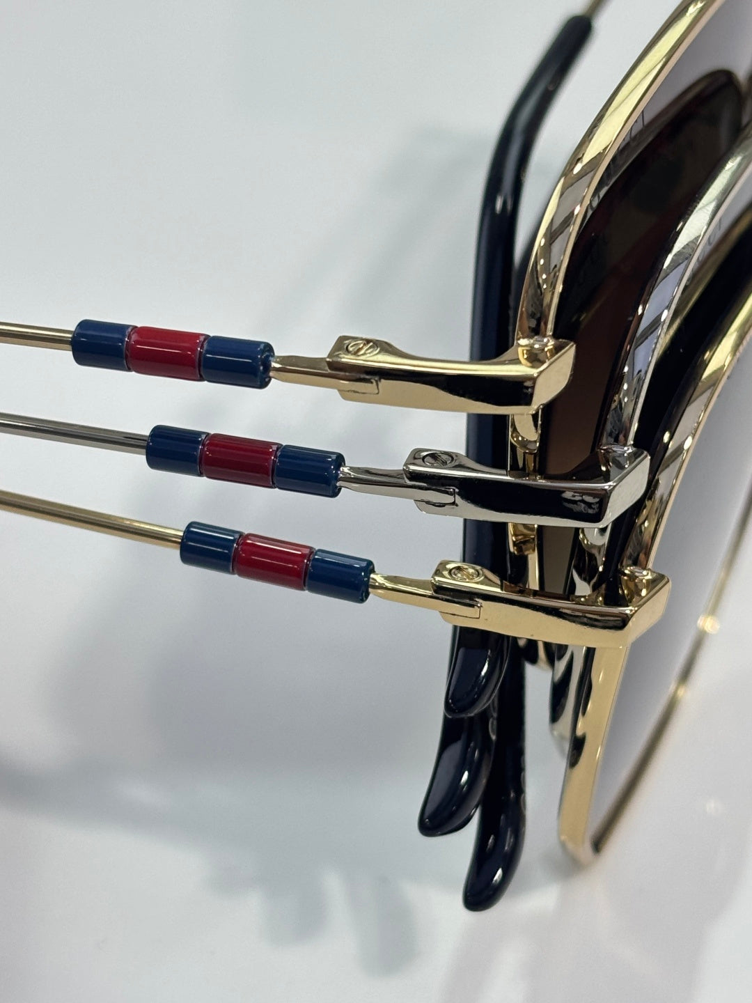 Gold-tone sunglasses temples with red and blue beaded accents near hinge