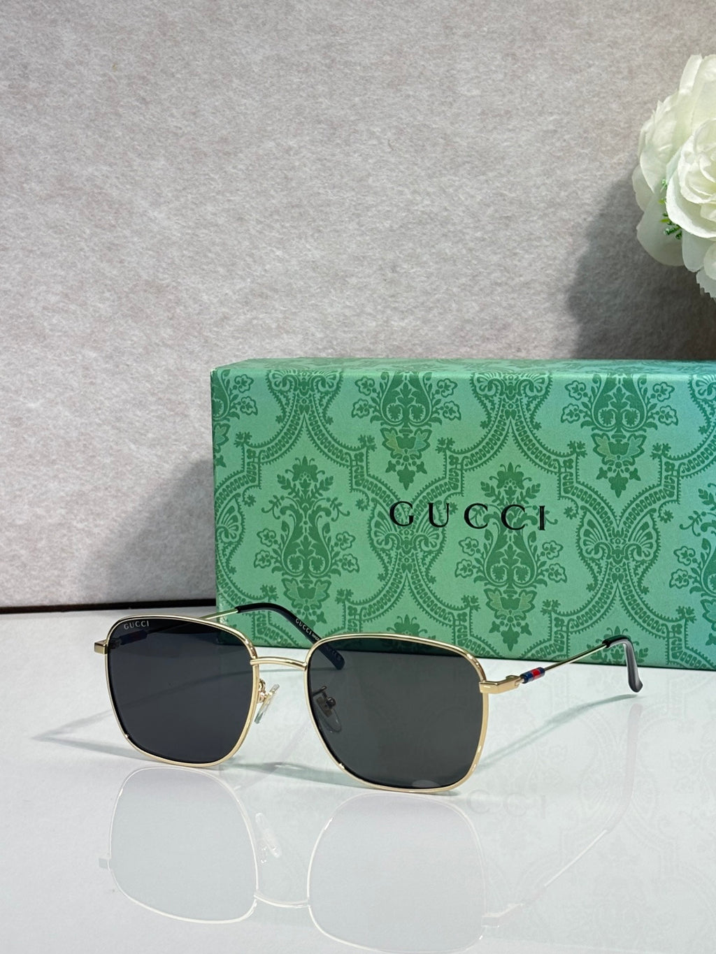 Gucci square sunglasses with gold frame and dark lenses, Gucci lettering on temples