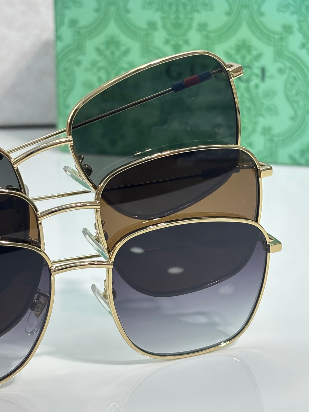 Gucci sunglasses pair stack with gold frames and dark lenses, temple details visible
