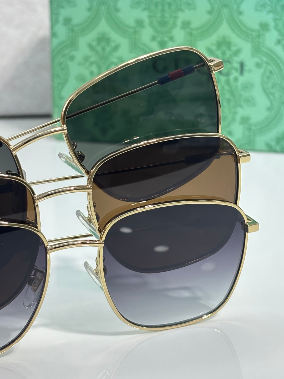 Gucci sunglasses pair stack with gold frames and dark lenses, temple details visible