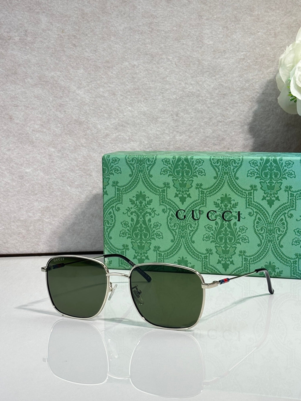 Gucci square sunglasses with gold frame and dark green-tinted lenses, logo on arms