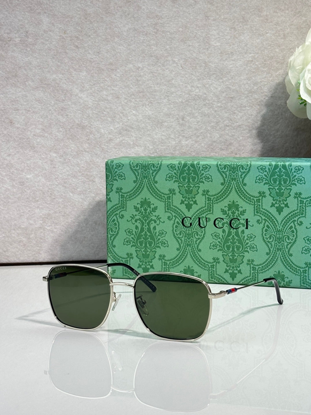 Gucci square sunglasses with gold frame and dark green-tinted lenses, logo on arms