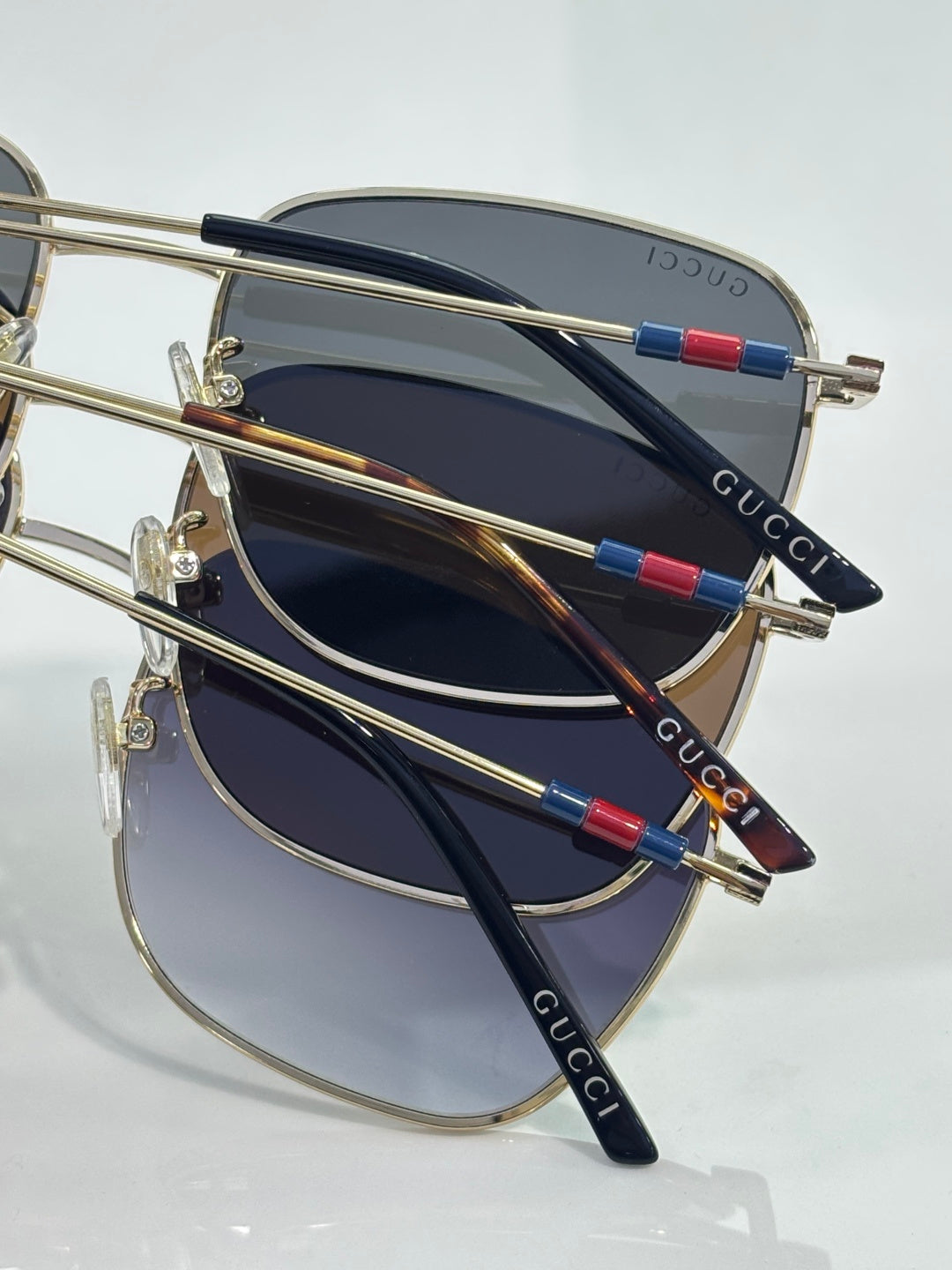 Gucci square sunglasses angled with gold frames, dark lenses, Gucci text on temples