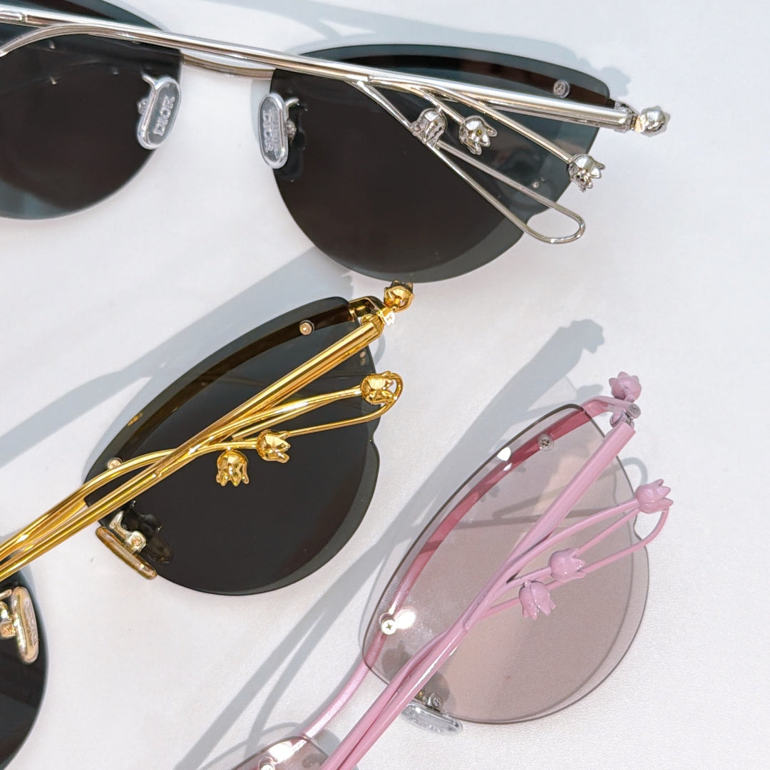 Sunglasses close-up with silver frame, black lenses, gold detail, and pink frame