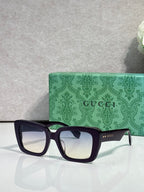 Gucci sunglasses with dark frames and clear lenses, beside a green patterned case