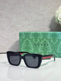 Gucci sunglasses with dark square frames and gray lenses, on a green logo case